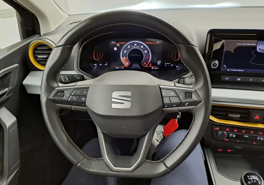 Vue intérieure centrée sur le volant de la SEAT Ibiza noir minuit 2024, avec tableau de bord numérique et détails jaunes autour des aérateurs.