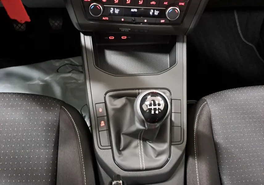 Gros plan sur la console centrale de la SEAT IBIZA 2024 noir minuit, mettant en valeur le levier de vitesse manuel et les commandes de climatisation.