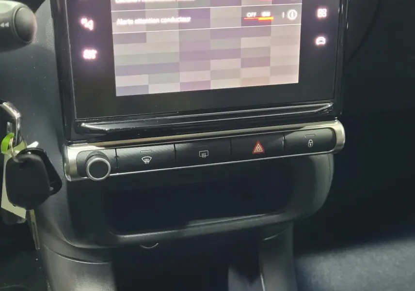 Gros plan sur l’écran tactile central et la console noire de la Citroën C3 beige, avec clé insérée à gauche.