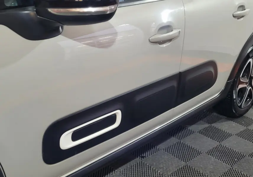 Vue latérale côté gauche d'une Citroën C3 beige 2022 avec protections noires distinctives sur les portes.
