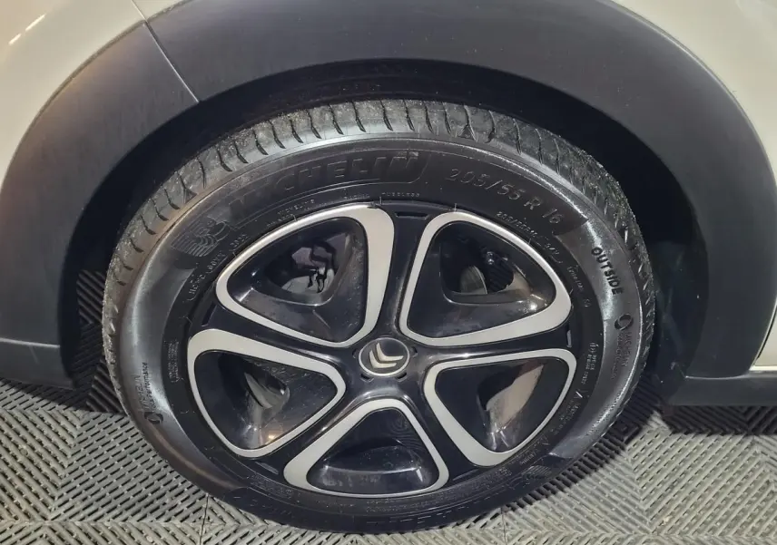 Gros plan sur la roue avant droite d'une Citroën C3 beige, mettant en valeur la jante noire et argentée au design moderne.