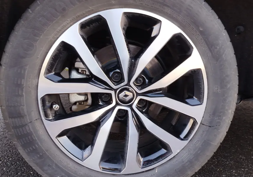 Gros plan sur la jante alliage bicolore noir et argent avec logo Renault au centre du Renault Kadjar gris Titanium.