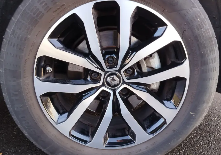 Gros plan sur la jante alliage bicolore noire et argentée avec logo Renault au centre du Renault Kadjar gris Titanium.