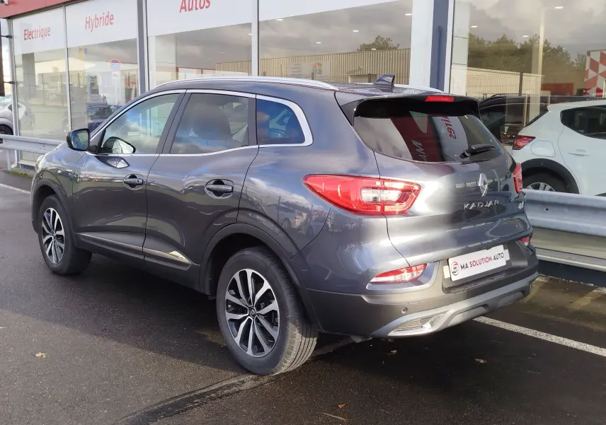 Renault Kadjar gris titanium vu en 3/4 arrière droit, avec jantes alliage et feux arrière allumés.