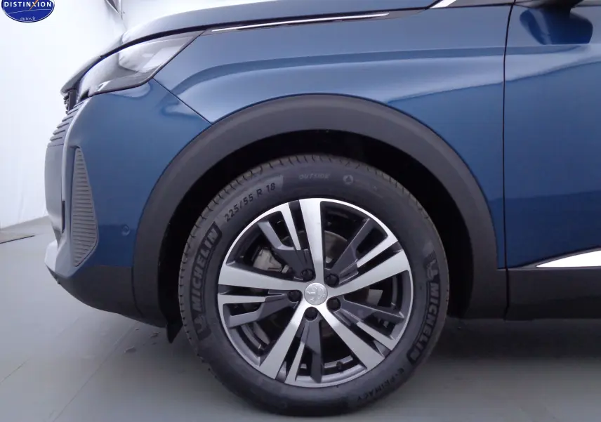 Gros plan sur la roue avant gauche d'un Peugeot 3008 bleu Célèbes Métal avec jante alliage bicolore et pneu Michelin.