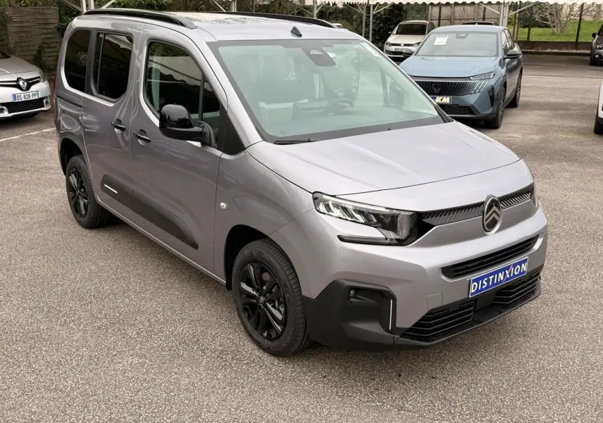 Vue 3/4 avant droit d'un Citroën Berlingo gris Artense 2025 avec jantes noires et calandre moderne sur parking.