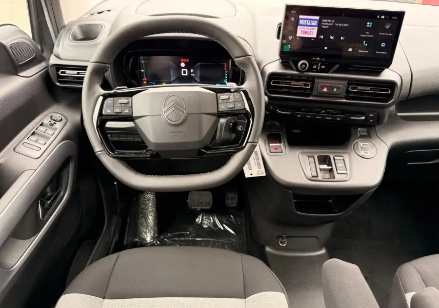 Vue intérieure avant du poste de conduite du Citroën Berlingo 2025, avec volant multifonction et écran tactile central.