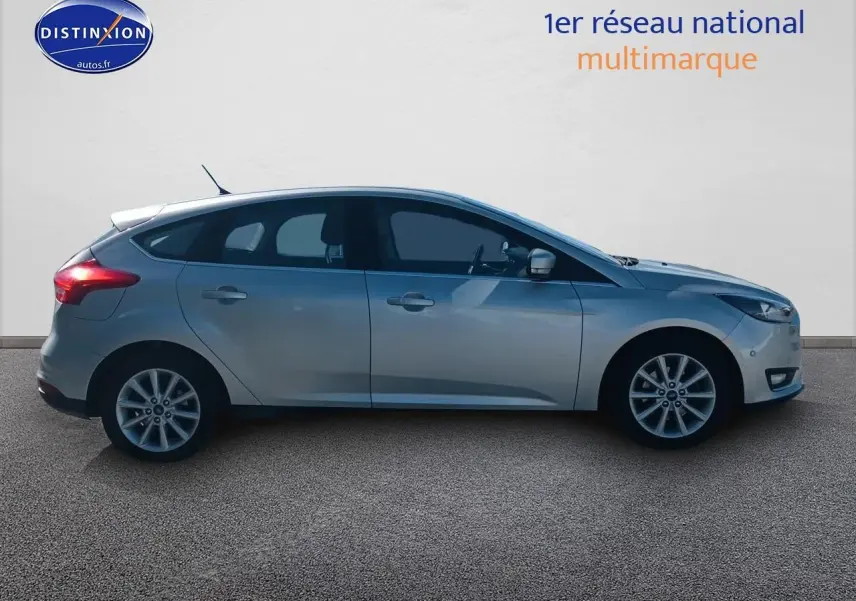 Profil côté gauche d'une Ford Focus gris clair 2017 avec jantes alu sur fond neutre.