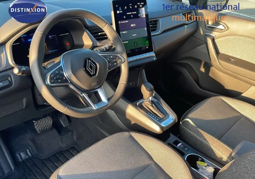 Intérieur du Renault Captur E-Tech hybride 2025, vue du poste de conduite avec volant multifonction et écran tactile vertical.