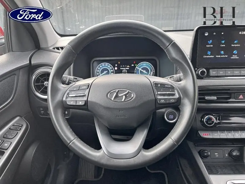 Vue intérieure centrée sur le volant cuir noir du Hyundai Kona 2022 avec tableau de bord numérique et écran tactile.