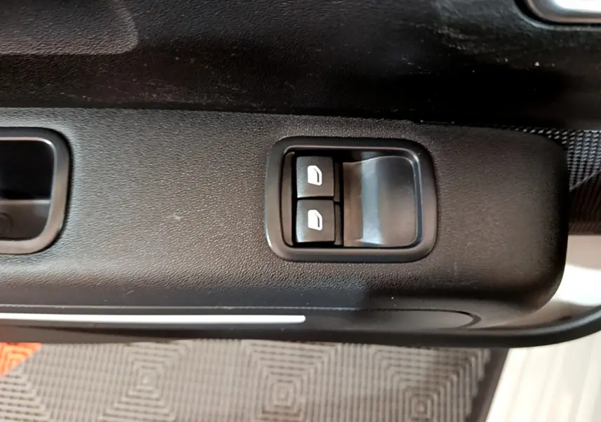 Gros plan sur les commandes des vitres électriques côté conducteur de la Citroën C3 beige, intérieur noir.