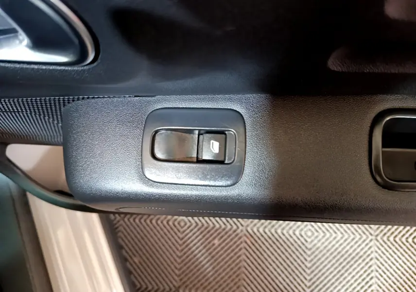 Gros plan sur le bouton de commande de la vitre électrique côté conducteur d'une Citroën C3 beige 2022.
