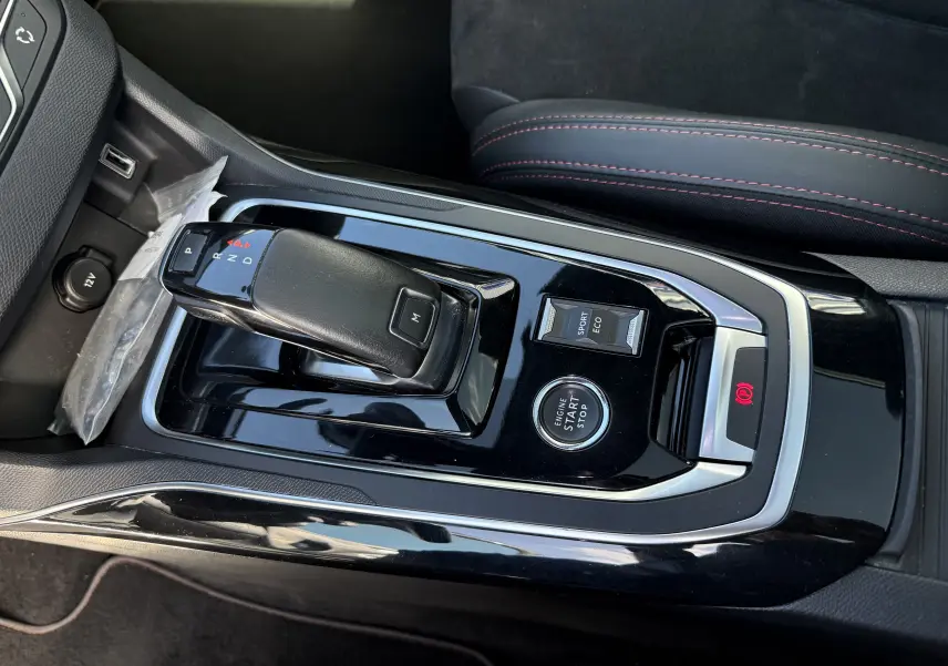 Gros plan sur la console centrale de la Peugeot 308 SW blanche nacrée, avec levier de vitesse automatique et boutons Start/Stop, Sport et Eco.