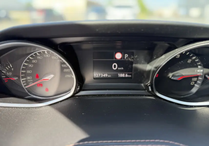 Vue rapprochée du tableau de bord numérique et des compteurs du Peugeot 308 SW blanc nacré, affichant 127349 km.