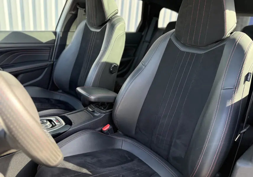 Vue intérieure rapprochée des sièges avant en cuir noir avec surpiqûres rouges du Peugeot 308 SW 2021.