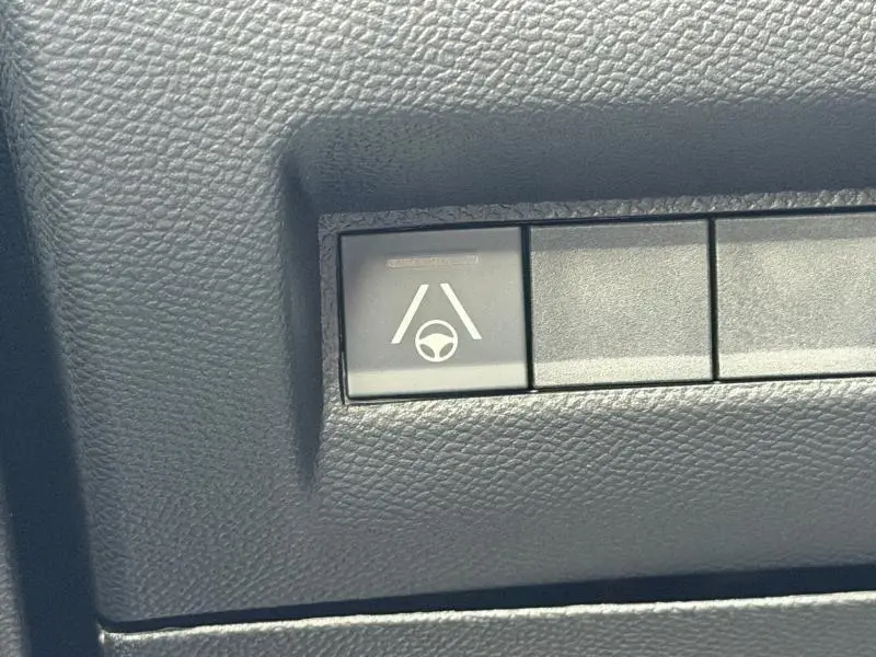 Bouton de commande d'aide au maintien de voie sur tableau de bord noir du Peugeot 2008 Hybrid bleu 2025.