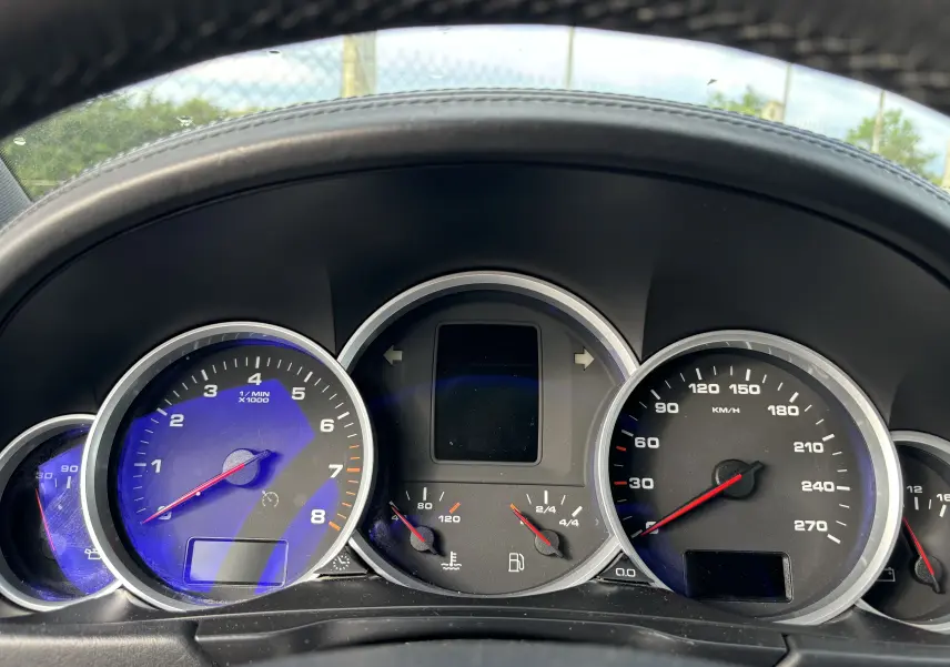 Vue rapprochée du tableau de bord noir du Porsche Cayenne S 4,8L V8 2007 avec compte-tours et compteur de vitesse.