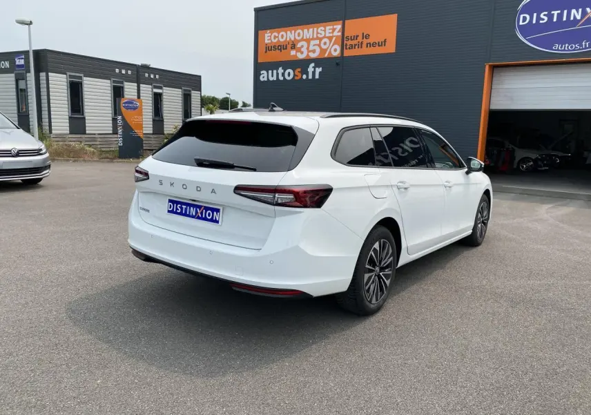 Vue 3/4 arrière droite d'une Skoda Superb Combi blanche pure avec vitres surteintées et jantes alliage noires polies.