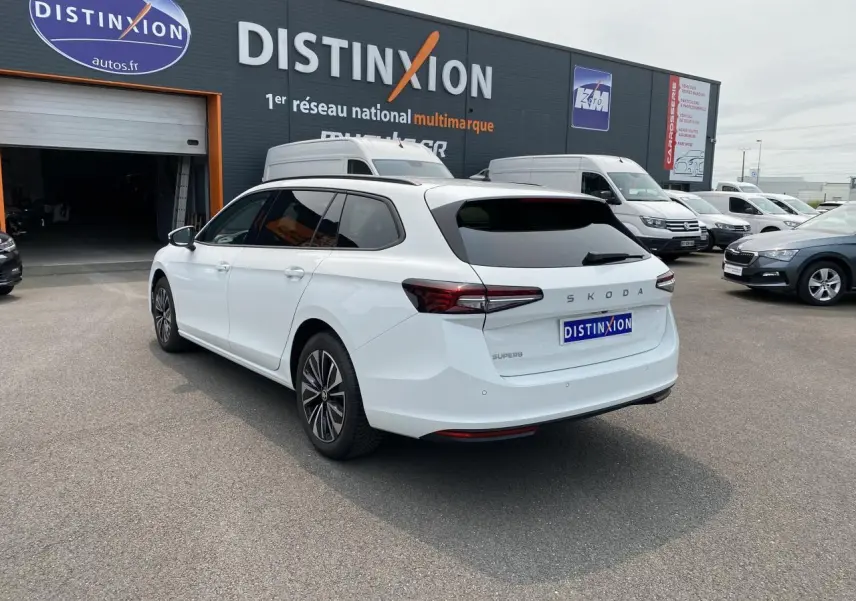 Vue 3/4 arrière droite d'une Skoda Superb Combi blanche pure avec vitres surteintées et jantes alliage noires polies.