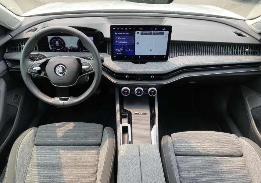 Intérieur de la Skoda Superb Combi 2024 vu de face, tableau de bord moderne avec écran tactile et volant multifonction noir.