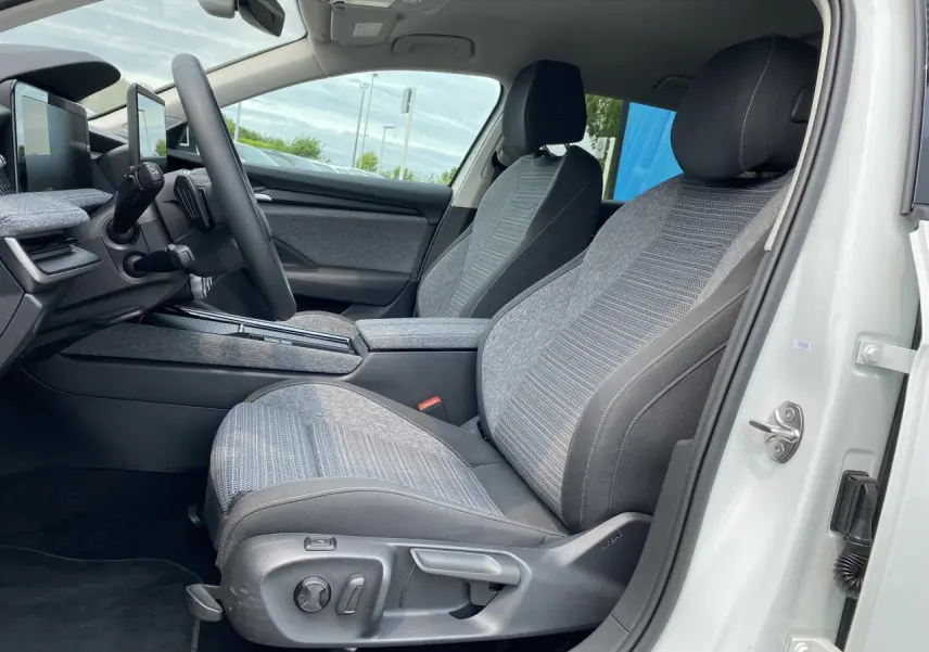 Intérieur côté conducteur de la Skoda Superb Combi blanc pure 2024, sièges tissu gris avec commandes électriques visibles.