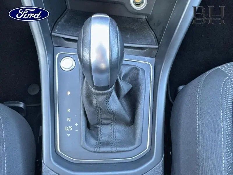 Le levier de vitesses automatique noir vu de dessus entre deux sièges en tissu gris, sans éléments extérieurs visibles.