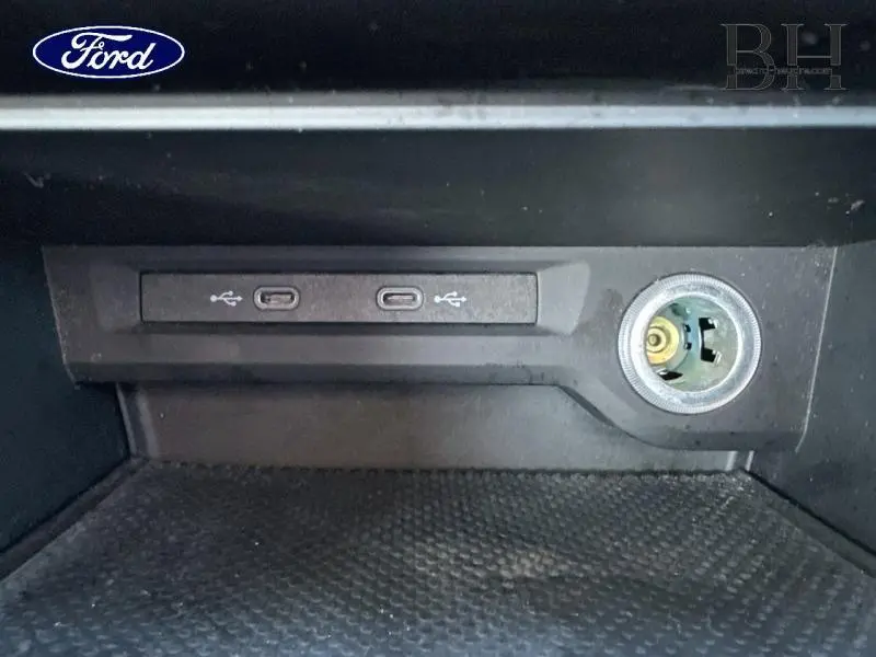 Gros plan sur les ports USB et prise 12V dans un espace de rangement intérieur noir, sans lien visible avec un Volkswagen Touran.