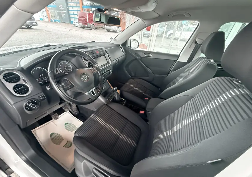 Vue intérieure côté conducteur du Volkswagen Tiguan 2.0 TDI 140 avec sièges tissu noir et volant cuir multifonction.