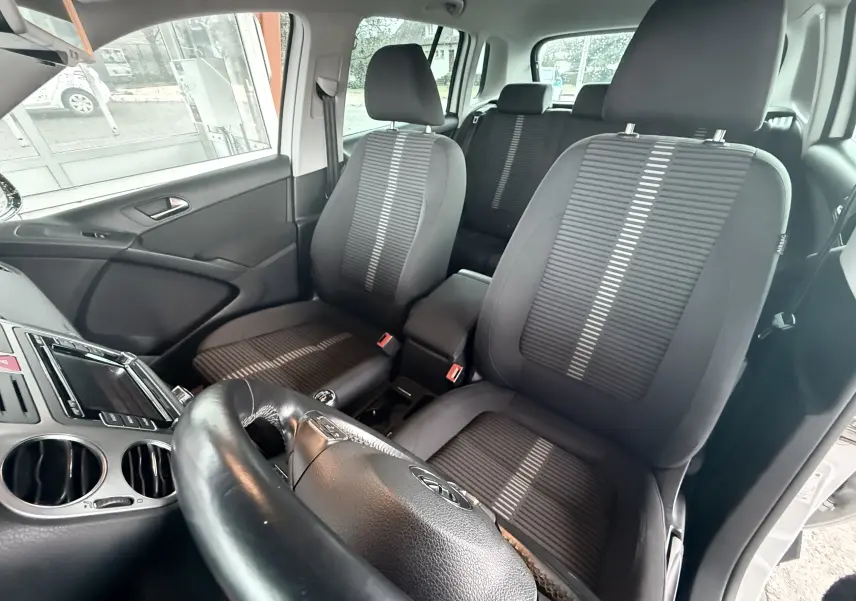 Vue intérieure avant du Volkswagen Tiguan 2.0 TDI blanc de 2010, sièges tissu noir avec volant cuir multifonction.
