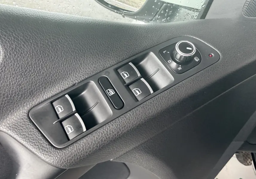 Détail des commandes de lève-vitres et réglage des rétroviseurs sur la porte côté conducteur d’un Volkswagen Tiguan 2.0 TDI blanc.
