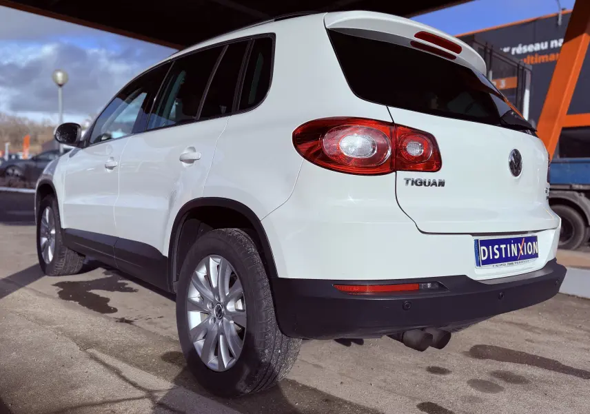 Vue 3/4 arrière droite d'un Volkswagen Tiguan blanc de 2010 avec jantes alliage et feux arrière ovales rouges.