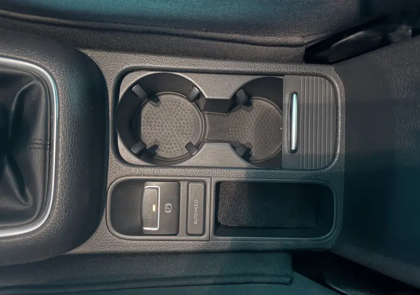 Vue rapprochée de la console centrale noire du Volkswagen Tiguan 2.0 TDI avec porte-gobelets et commandes électroniques.