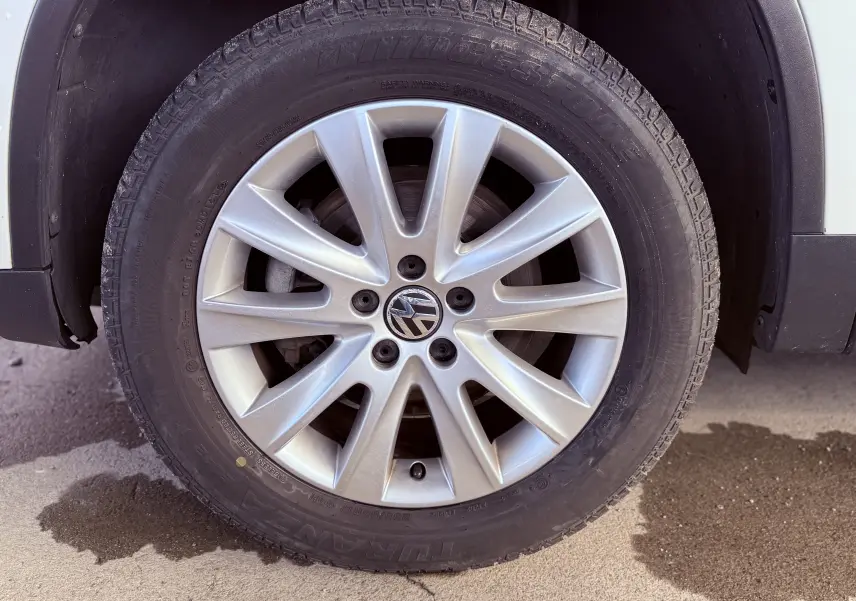Gros plan sur la roue avant droite blanche d’un Volkswagen Tiguan 2.0 TDI 2010 avec jante alliage argentée.