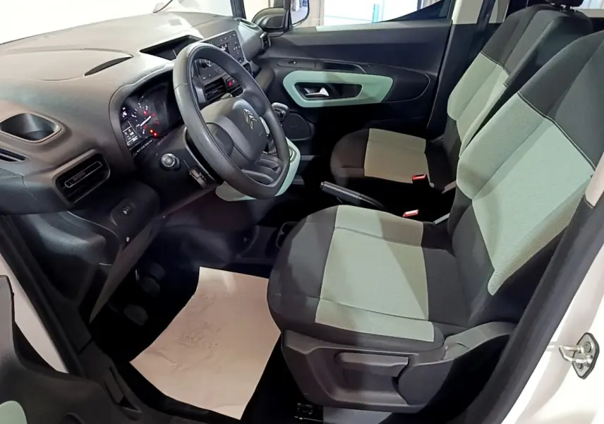 Vue intérieure côté conducteur du Citroën Berlingo blanc 2019, montrant le tableau de bord et sièges bicolores gris et noir.