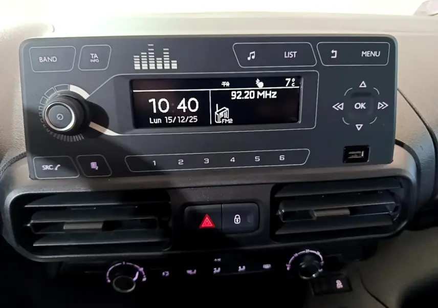 Vue rapprochée du tableau de bord noir du Citroën Berlingo XL blanc, affichant l’horloge et la radio digitale.