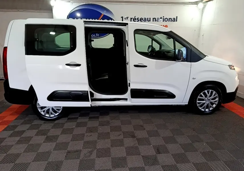 Vue de profil droit d'un Citroën Berlingo XL blanc 2019 avec porte coulissante arrière ouverte en intérieur showroom.