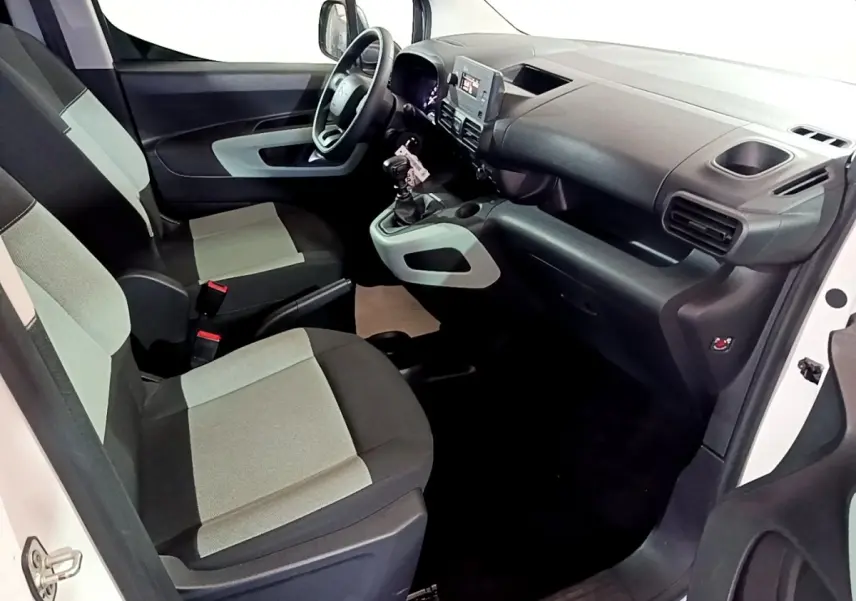 Vue intérieure côté conducteur du Citroën Berlingo XL blanc, montrant sièges tissu bicolore et tableau de bord moderne.