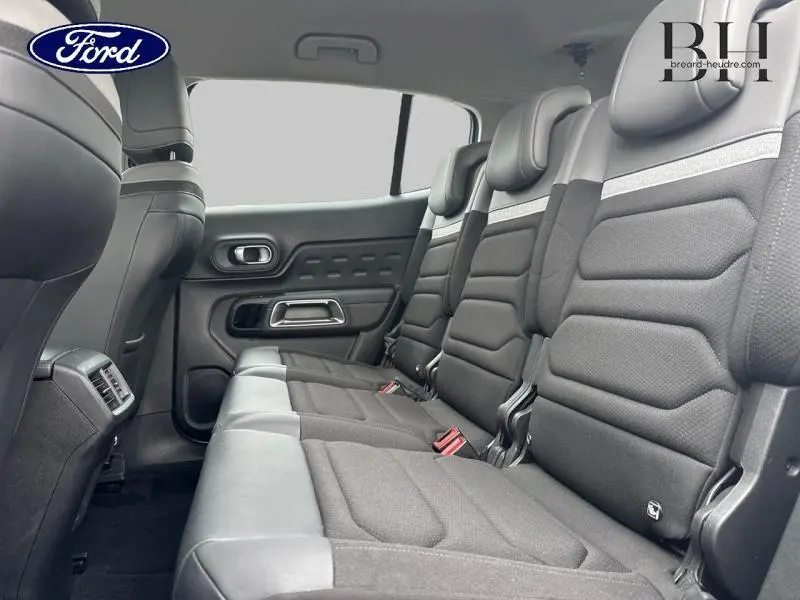 Vue intérieure des trois sièges individuels arrière gris foncé du Citroën C5 Aircross 2023, avec accoudoirs et ceintures visibles.