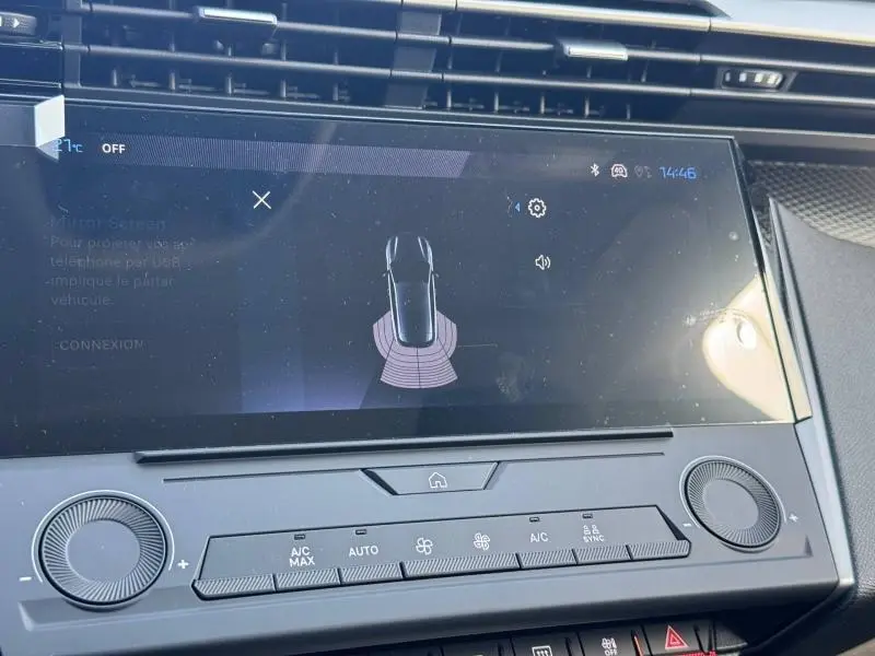 Écran tactile central de la Peugeot 308 blanc Okénite, affichant l'aide au stationnement avec capteurs actifs.