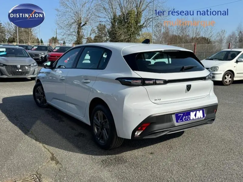 Peugeot 308 blanc Okénite vue 3/4 arrière droit, feux arrière LED et jantes alu visibles en extérieur.