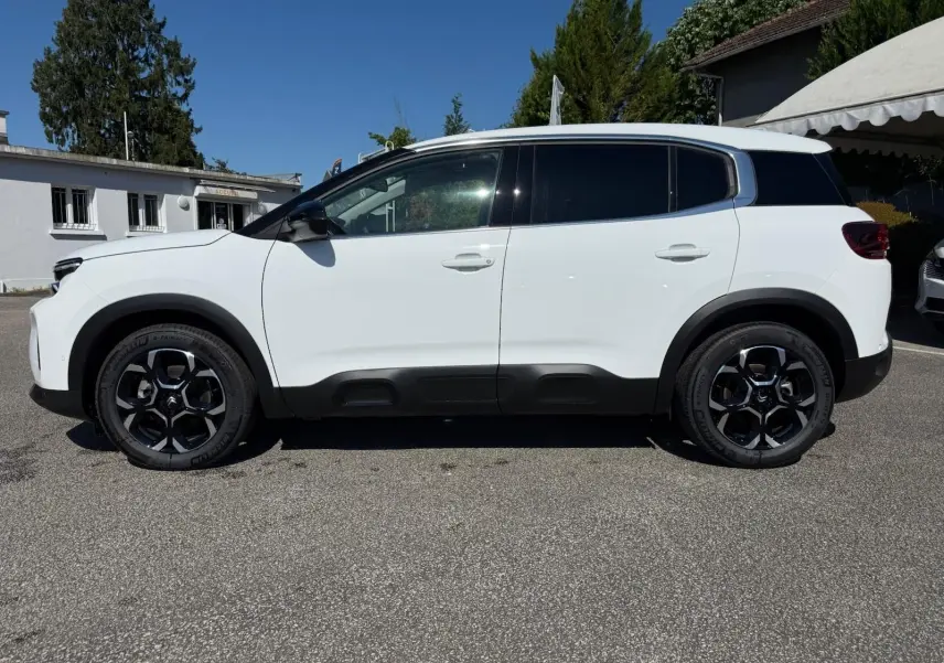 Profil côté gauche d'un Citroën C5 Aircross blanc Banquise avec protections noires sur les bas de caisse et arches de roues.