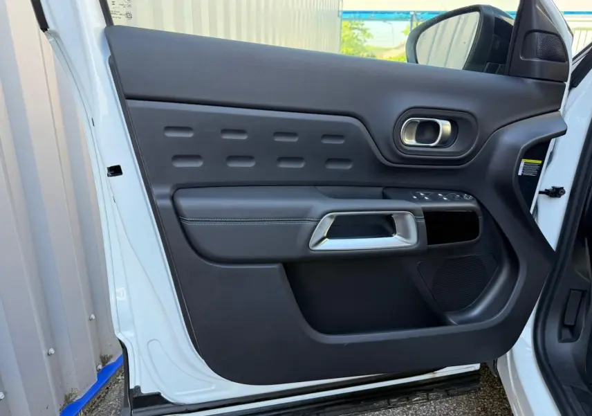 Vue rapprochée de la porte avant gauche blanche banquise du Citroën C5 Aircross 2024 avec garniture noire et poignée argentée.