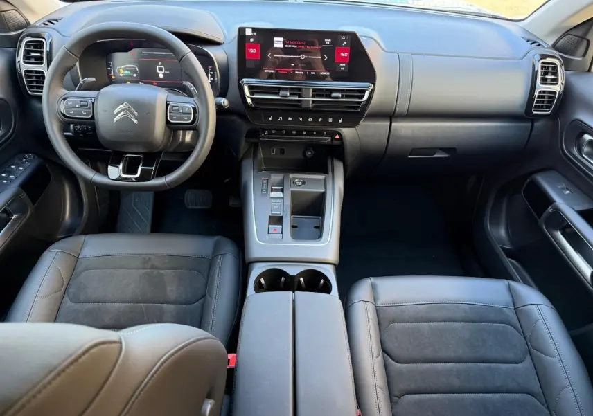 Intérieur du Citroën C5 Aircross hybride 2024 vu de face, tableau de bord moderne avec écran tactile et sièges cuir noir.