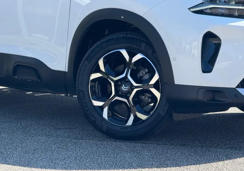 Gros plan sur la roue avant droite blanche banquise du Citroën C5 Aircross 2024 avec jante noire et argentée design urbain.