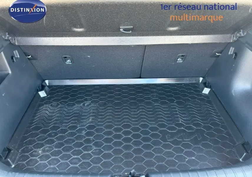 Coffre spacieux du Kia Stonic gris météore 2024, vue intérieure avec tapis de sol en caoutchouc à motif hexagonal.