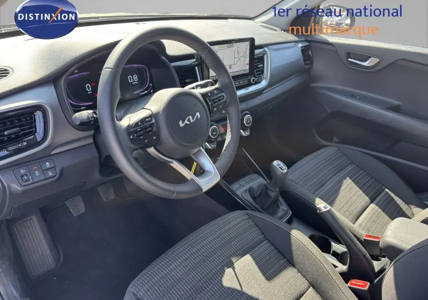 Vue intérieure côté conducteur du Kia Stonic 2024 avec volant multifonction, tableau de bord digital et sellerie tissu noire.