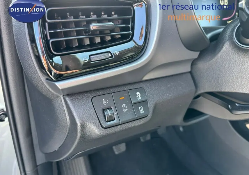 Détail du tableau de bord côté gauche du Kia Stonic gris météore 2024 avec commandes d'éclairage et sécurité.