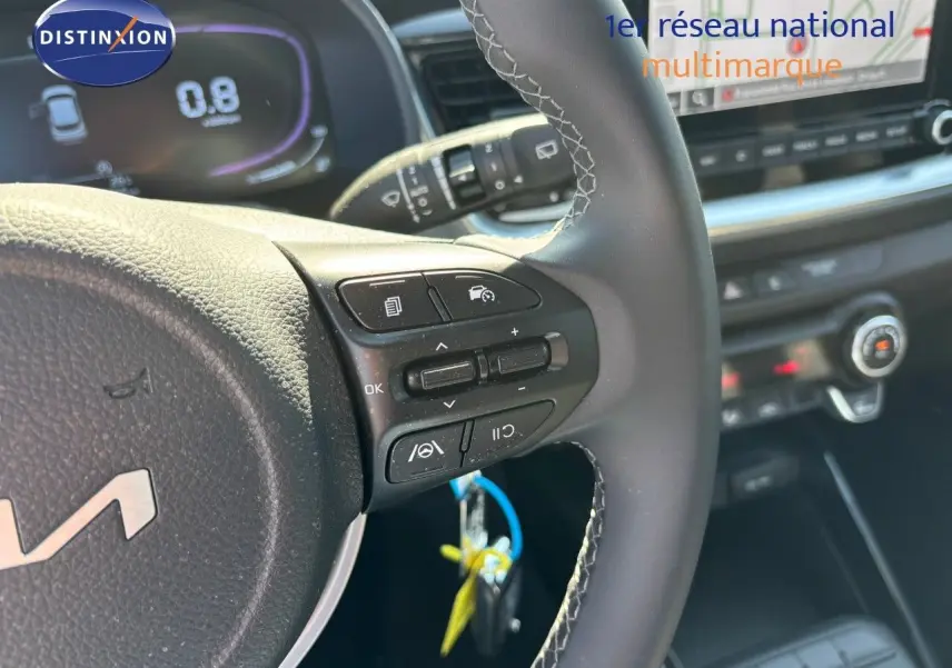 Gros plan sur le volant cuir avec commandes multifonctions du KIA STONIC gris météore 2024, tableau de bord numérique visible.