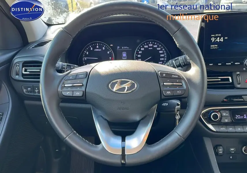 Vue frontale du volant cuir multifonction d'une Hyundai i30 gris argent 2024 avec tableau de bord et écran tactile.