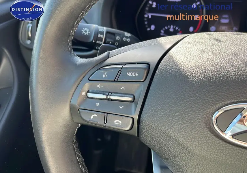 Gros plan sur les commandes audio au volant cuir gris de la Hyundai i30 2024 hybride essence.